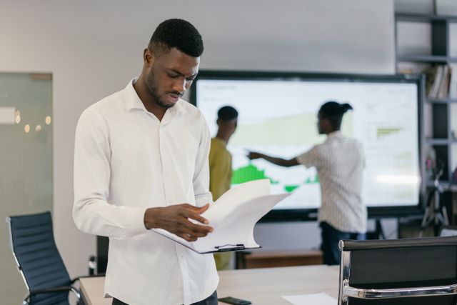 Man in office reading documents with colleagues