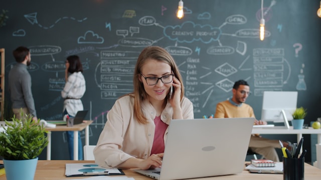 Woman on phone working on laptop