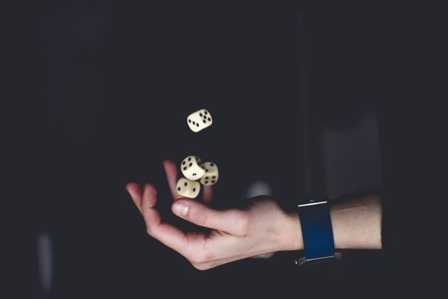 close-up of a hand tossing several dice against a dark background