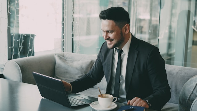 man smiles while working on laptop