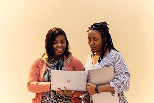 Two women collaborating with laptops